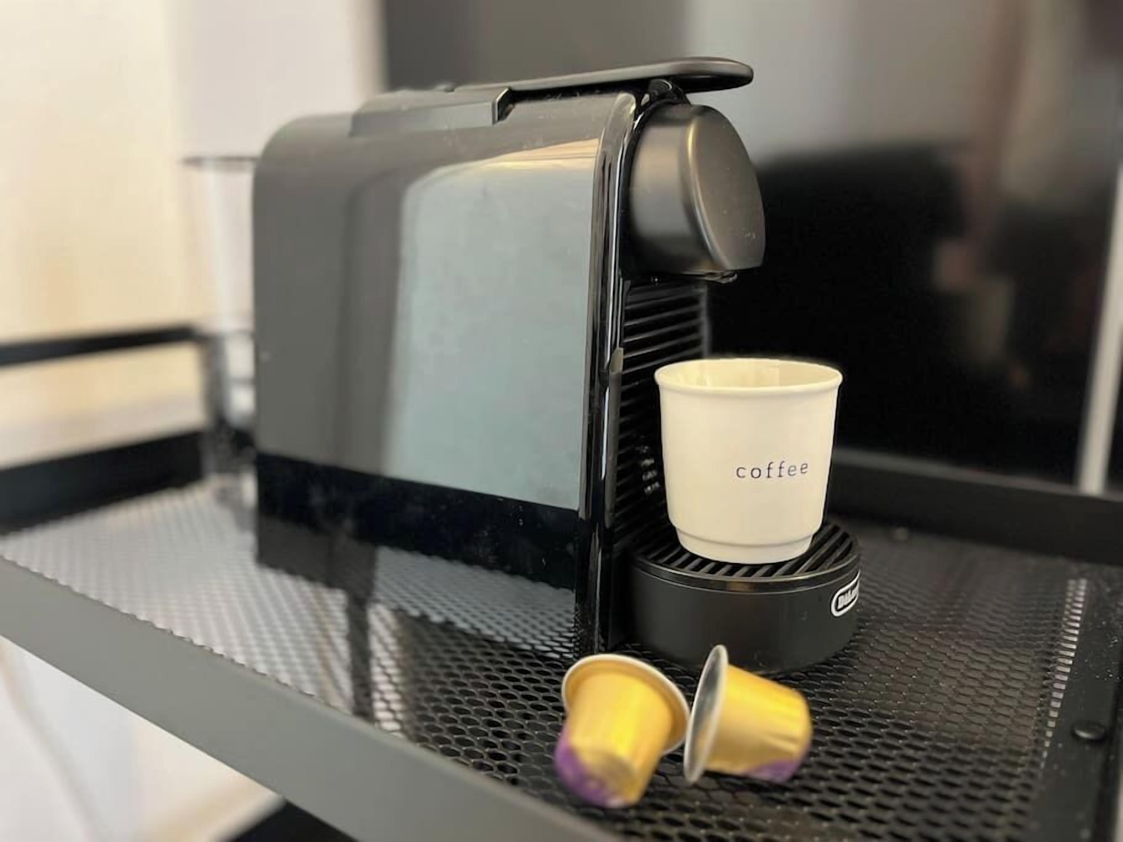 A coffee machine with a cup holder and two disposable cups on a metal surface.