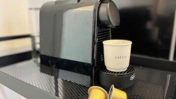 A coffee machine with a cup holder and two disposable cups on a metal surface.