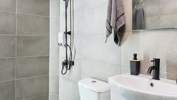A modern bathroom with a shower, toilet, and sink.