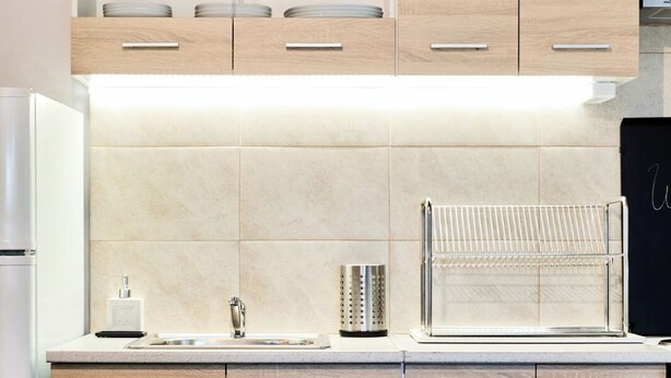 A modern kitchen with wooden cabinets, a built-in oven, and a stainless steel sink. - West Garden in Aigio (Aigio)