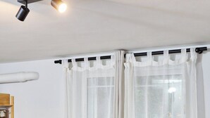 A dining area with a wooden table, four grey chairs, a small wooden side table with snacks, and a window with white curtains. - West Garden in Aigio (Aigio)