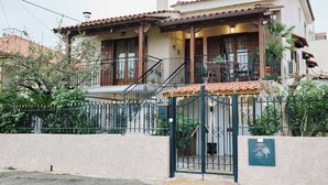 A two-story house with a tiled roof, a balcony, and a gated entrance. - West Garden in Aigio (Aigio)
