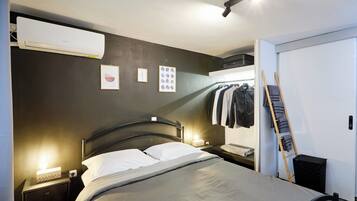 Une chambre à coucher comprenant un lit, des tables de chevet, une armoire, une échelle et un appareil de climatisation.