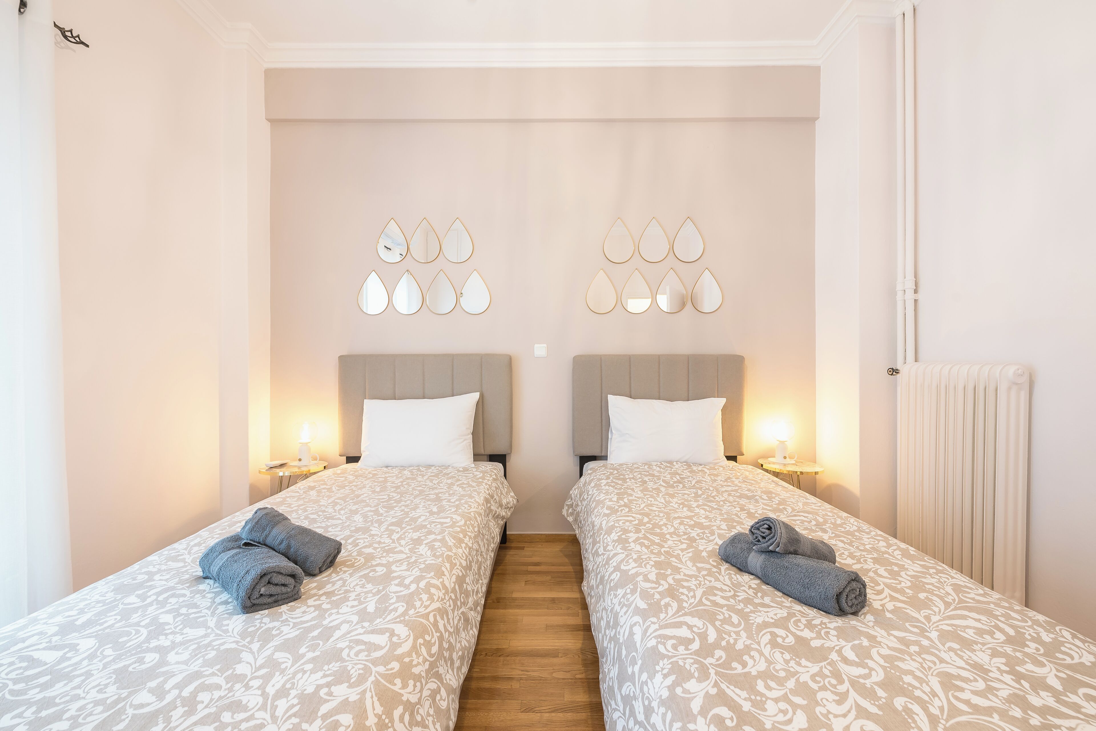 A twin room with two beds, each with a headboard, a bedside table, and a lamp.