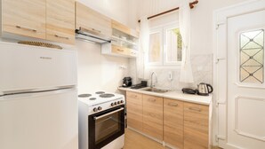 A modern kitchen with a white refrigerator, a stove, and wooden cabinets.