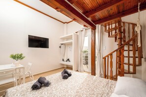 Ein Schlafzimmer mit einem Bett, einem Schreibtisch, einem Stuhl, einem Fernseher und einer Holztreppe.