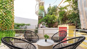A balcony with two black wicker chairs, a small round table, and a potted plant.