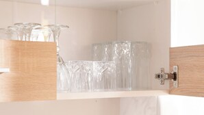A modern kitchen with white cabinets, a marble countertop, and a wooden backsplash.