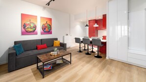A modern living room with a grey sofa, a wooden coffee table, and two vibrant paintings on the wall. - Alkis Luxury By Greece Apartments (Zografou)