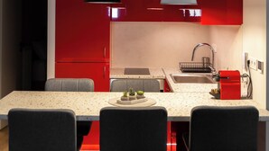 A modern kitchen with red cabinets, a white countertop, and three black bar stools. - Alkis Luxury By Greece Apartments (Zografou)