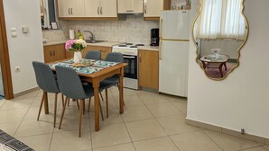 A modern kitchen with wooden cabinets, a dining table with chairs, a coffee maker, and a decorative mirror.