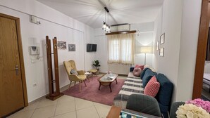 A living room with a sofa, armchairs, a coffee table, a TV, and a lamp.