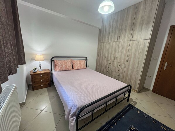 A bedroom with a bed, bedside table, lamp, wardrobe, and radiator.