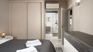 A modern bedroom with a large bed, a bedside table with a lamp, and a walk-in closet. - Lagos Terrace With Pool by Homing (Lagos)