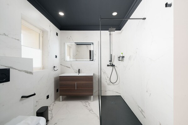 A modern bathroom with a marble floor, a wooden vanity, a mirror, and a shower area. - Lagos Terrace With Pool by Homing (Lagos)
