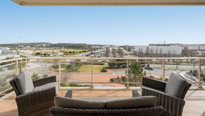 A balcony with wicker furniture and a view of a cityscape including a McDonald's. - Lagos Terrace With Pool by Homing (Lagos)