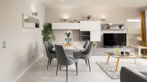 A modern living room with a dining area, a flat-screen TV, and a sofa. - Lagos Terrace With Pool by Homing (Lagos)