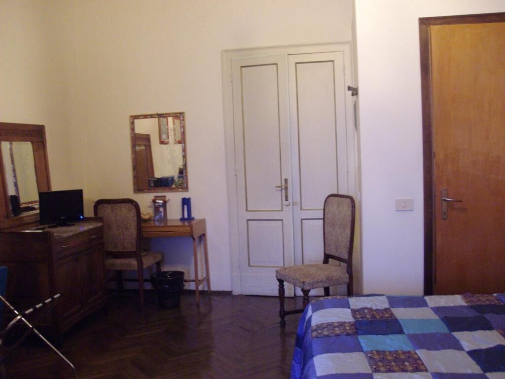 Una camera da letto con un letto, una scrivania, una sedia, un comò, uno specchio e una porta.