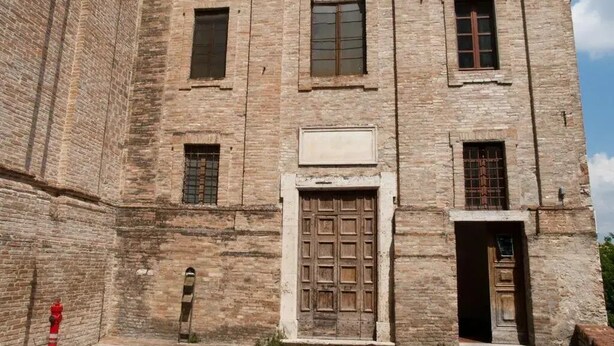 A historic stone building with a central arched window, a large wooden door, and multiple smaller windows. - Anna (Perugia)