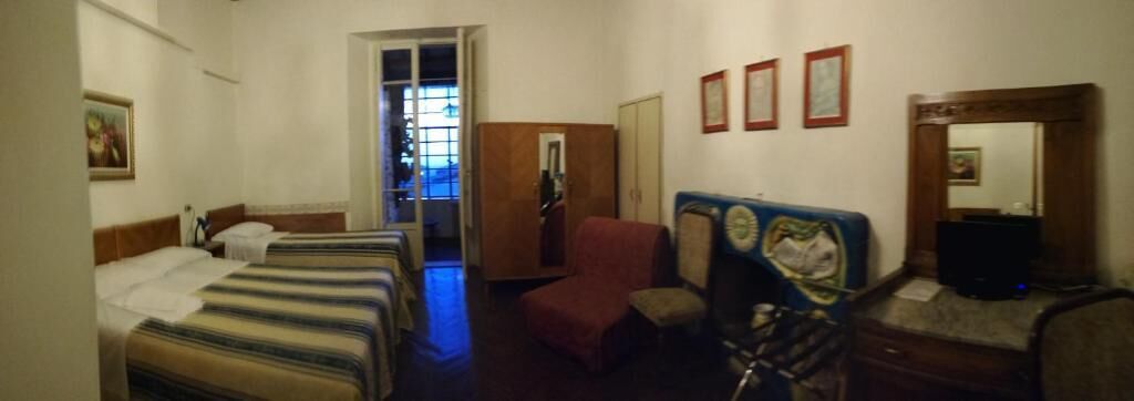 Ein Hotelzimmer mit zwei Betten, einem Schreibtisch, einem Stuhl, einem Fernseher und einem Fenster mit Blick.