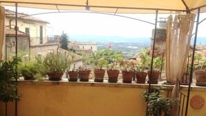 A balcony with a table and chairs, potted plants, and a view of the city. - Anna (Perugia)