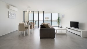 A modern living room with a sofa, TV, dining table, and chairs. - Portimão Ocean Breeze by Homing (Lagoa)
