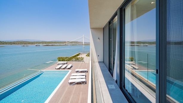 A balcony with a pool, lounge chairs, and a view of a bridge and water. - Portimão Ocean Breeze by Homing (Lagoa)
