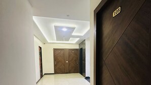 Un couloir doté d’un plafond au design moderne, d’une porte en bois portant un numéro et d’un sol carrelé.