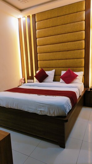 A modern hotel room with a large bed, wooden headboard, and a red accent pillow. - Hotel SMR Palace- Rooftop View Taj Mahal (Agra)