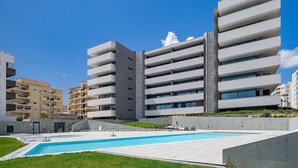 A modern apartment building with a swimming pool and a well-maintained lawn. - Lagos Deluxe 2 With Pool by Homing (Lagos)