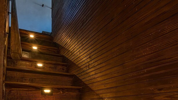 A wooden staircase with built-in lighting, leading to an upper level.