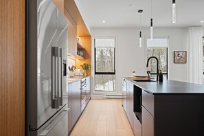A modern kitchen with a large island, stainless steel appliances, and a view of the outdoors.