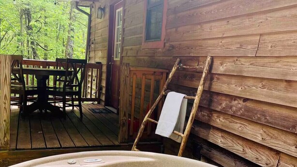 Una cabaña de madera con jacuzzi, una mesa de comedor y sillas.