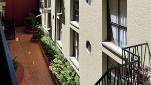 A multi-story residential building with balconies, a red building adjacent to it, and a small courtyard with plants. - Modern apartment in La Candelaria - Bogota (Bogotá)