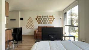 A modern bedroom with a large bed, a desk with a chair, a sofa, and a TV. - Modern apartment in La Candelaria - Bogota (Bogotá)