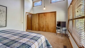Une chambre à coucher avec un lit, un bureau, une télévision et une armoire.