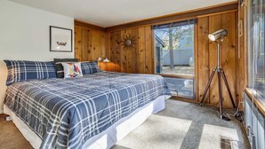 Une chambre avec un grand lit, des murs en bois, une fenêtre et un lampadaire.