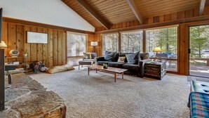 Un salon chaleureux avec une cheminée, des murs en bois et de grandes fenêtres.