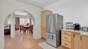 Eine moderne Küche mit einem Edelstahl-Kühlschrank, Holzschränken und einem Essbereich mit Tisch und Stühlen.