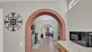 Eine Küche mit einer Ziegelbogenarchitektur, einer Mikrowelle, Schränken und einem Essbereich im Hintergrund.