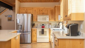 Una cocina con armarios de madera, electrodomésticos de acero inoxidable y una encimera blanca.