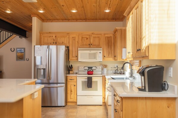 Une cuisine avec des meubles en bois, des appareils en acier inoxydable et un plan de travail blanc.