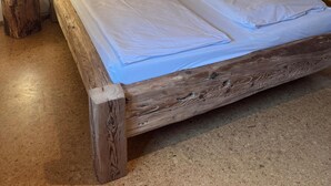 Ein hölzernes Bett mit weißen Leinen und zwei Nachttischlampen.