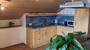 Eine Küche mit Holzausstattung, einem Spülbecken und einer Arbeitsplatte. An der Decke sind Lichterketten angebracht und auf der Arbeitsplatte steht eine Pflanze.