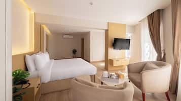 Una habitación de hotel con una cama, televisor, escritorio, silla y planta.