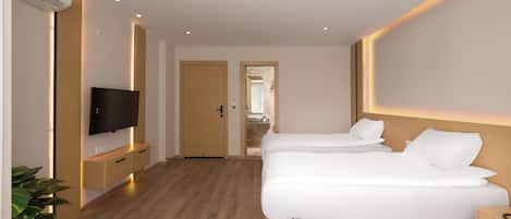 A hotel room with a wooden floor, a TV on a stand, two beds with white bedding, and a bathroom visible through an open door.