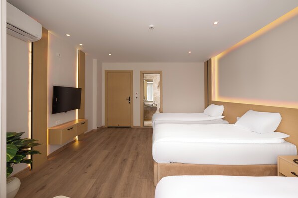 A hotel room with a wooden floor, a TV on a stand, two beds with white bedding, and a bathroom visible through an open door. - Elegance Grand City Hotel (Cairo)