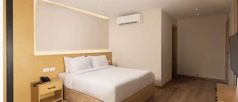Una habitación de hotel moderna con una cama de madera, una mesita de noche con un teléfono y un equipo de aire acondicionado en la pared.