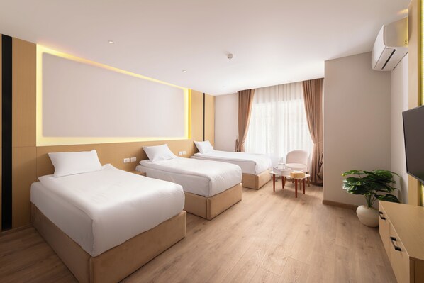 A hotel room with three single beds, a small table, a chair, and a TV. - Elegance Grand City Hotel  (Cairo)
