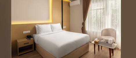A modern hotel room with a large bed, bedside table, and a small table with amenities.